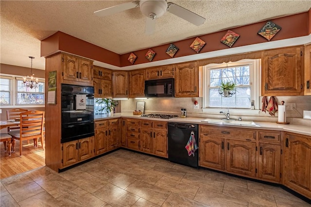 kitchen with black appliances, a warming drawer, brown cabinetry, and a sink