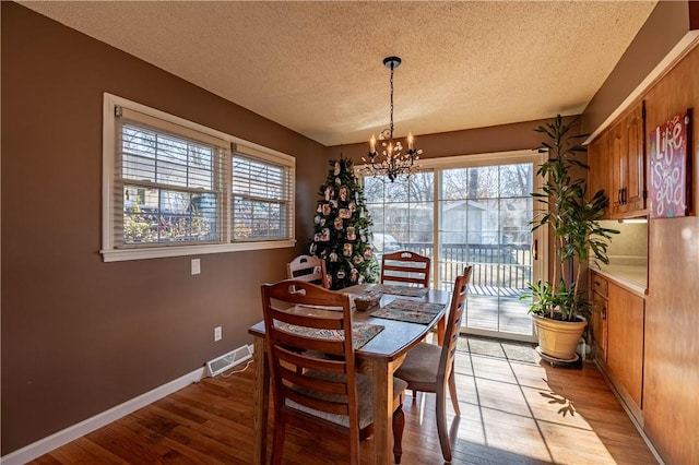 dining space with light wood finished floors, visible vents, baseboards, and a notable chandelier