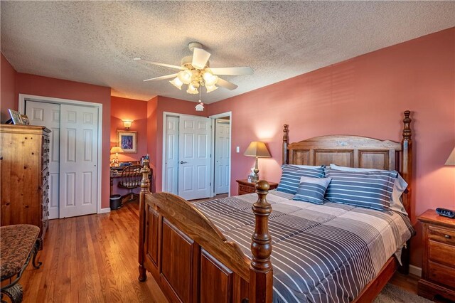 bedroom featuring light wood-style flooring, a textured ceiling, ceiling fan, and multiple closets