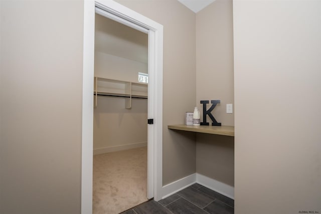 walk in closet with dark carpet