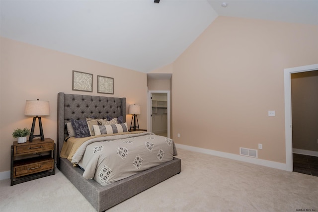 carpeted bedroom with high vaulted ceiling, a walk in closet, and a closet