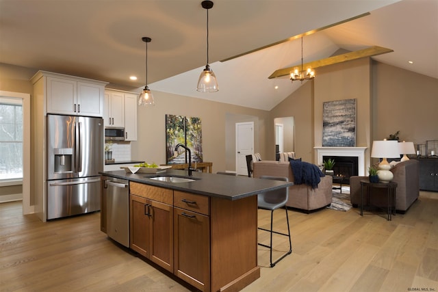 kitchen featuring sink, an island with sink, light wood-type flooring, white cabinets, and stainless steel appliances