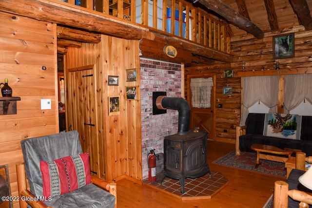 living room featuring wooden walls, hardwood / wood-style floors, a wood stove, and beamed ceiling