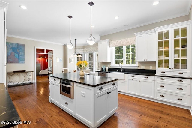 kitchen with a sink, dark countertops, stainless steel appliances, and crown molding