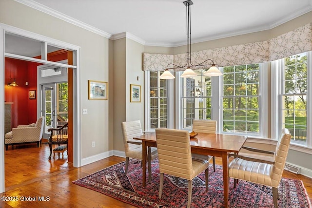 dining area featuring baseboards, wood finished floors, ornamental molding, and a healthy amount of sunlight