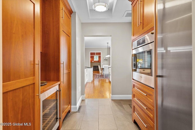 kitchen featuring stainless steel appliances, wine cooler, light tile patterned flooring, visible vents, and brown cabinetry
