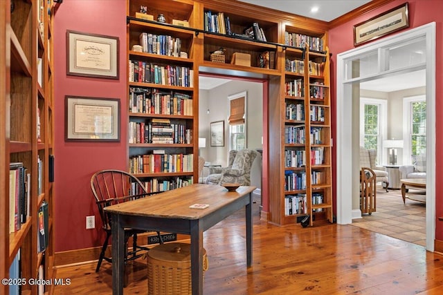 home office featuring ornamental molding, bookshelves, and wood-type flooring