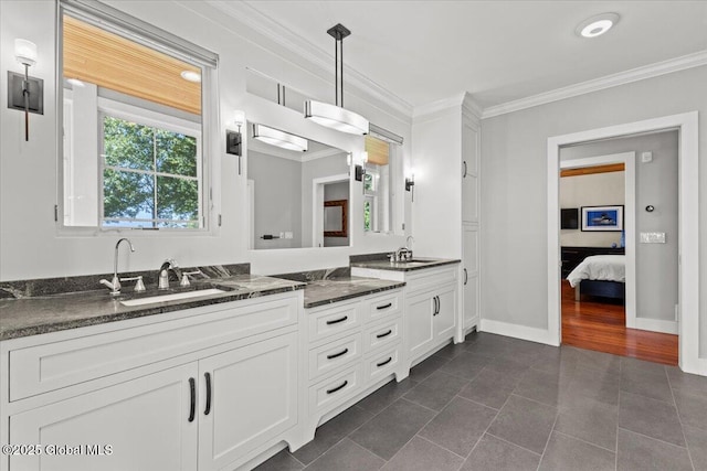 bathroom with baseboards, double vanity, ornamental molding, and a sink