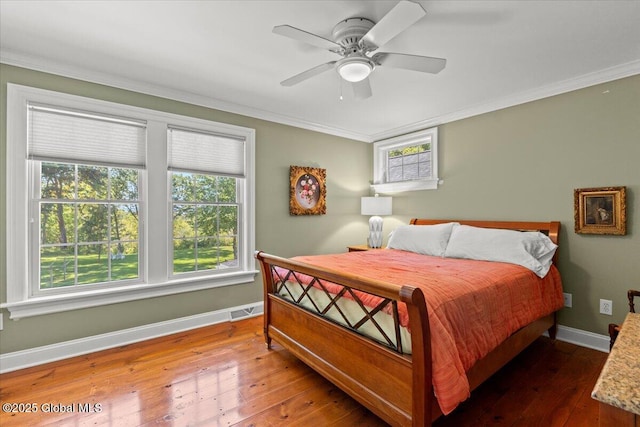 bedroom with visible vents, crown molding, hardwood / wood-style flooring, baseboards, and ceiling fan