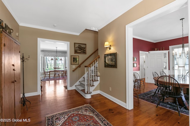 foyer with hardwood / wood-style floors, stairs, crown molding, and a chandelier