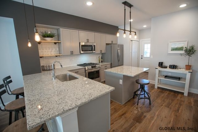 kitchen with sink, stainless steel appliances, dark wood-type flooring, and decorative light fixtures