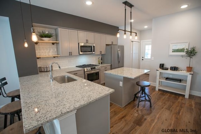 kitchen with light stone counters, stainless steel appliances, decorative light fixtures, and sink