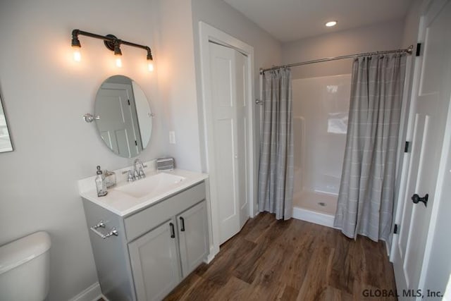 bathroom featuring vanity, hardwood / wood-style floors, a shower with curtain, and toilet