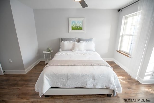 bedroom featuring ceiling fan, dark hardwood / wood-style floors, and multiple windows