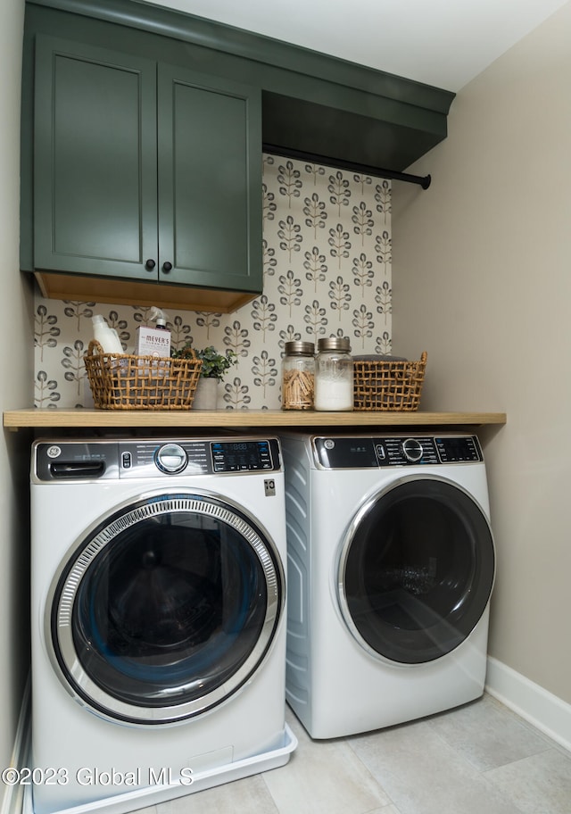 laundry area with washing machine and clothes dryer, cabinets, and light tile floors