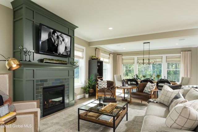 living room featuring plenty of natural light, a brick fireplace, ornamental molding, and a notable chandelier