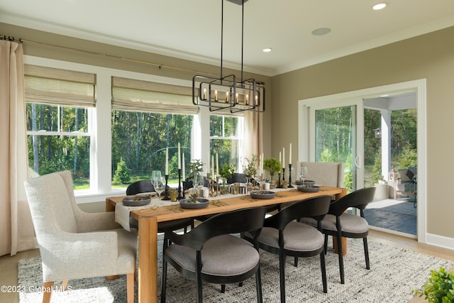 dining space with light hardwood / wood-style floors, ornamental molding, and a notable chandelier