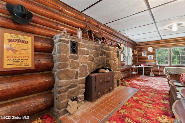 interior space with log walls and a paneled ceiling