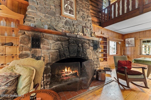 living room featuring wooden walls, wood-type flooring, and a fireplace