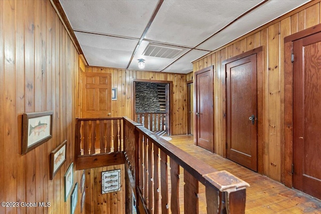 hall with wooden walls and light wood-type flooring