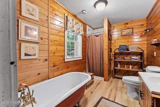 bathroom with vanity, wood-type flooring, wood walls, a bath to relax in, and toilet