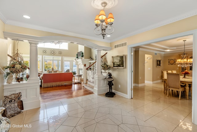 foyer with a chandelier, crown molding, decorative columns, and light tile flooring