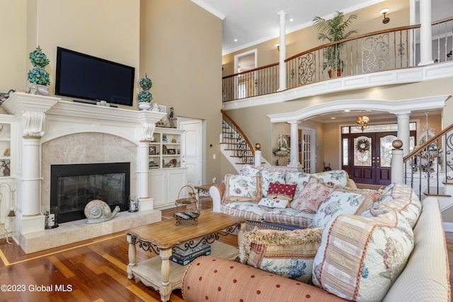 living room with hardwood / wood-style floors, decorative columns, a fireplace, crown molding, and french doors