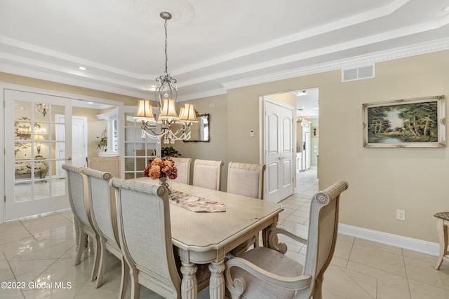 dining area featuring a tray ceiling, ornamental molding, light tile floors, and an inviting chandelier