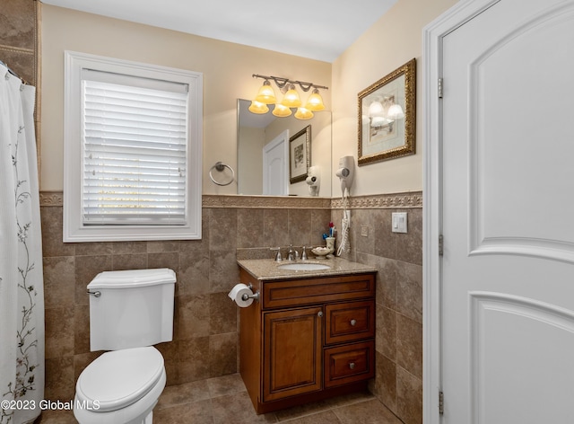 bathroom with tile walls, toilet, vanity, and tile flooring