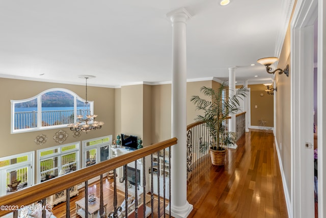 hallway featuring a notable chandelier, decorative columns, ornamental molding, and dark wood-type flooring