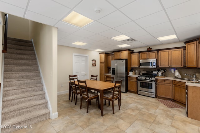 kitchen with stainless steel appliances, a paneled ceiling, and light tile floors