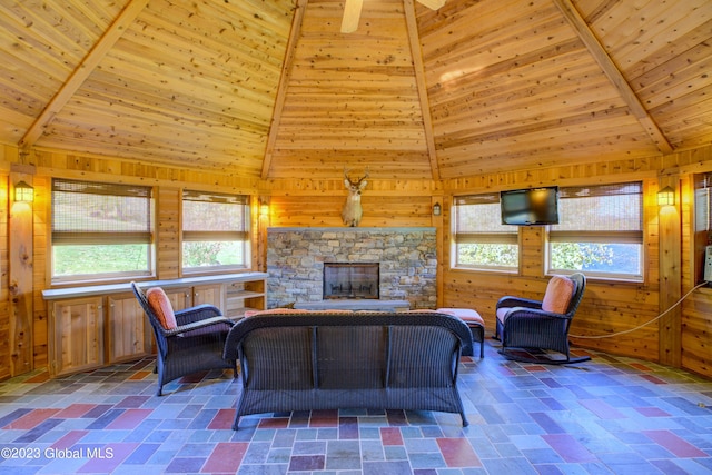 living room with dark tile flooring, high vaulted ceiling, wooden walls, and a wealth of natural light