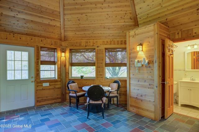 dining room with wood ceiling, sink, wood walls, and dark tile flooring