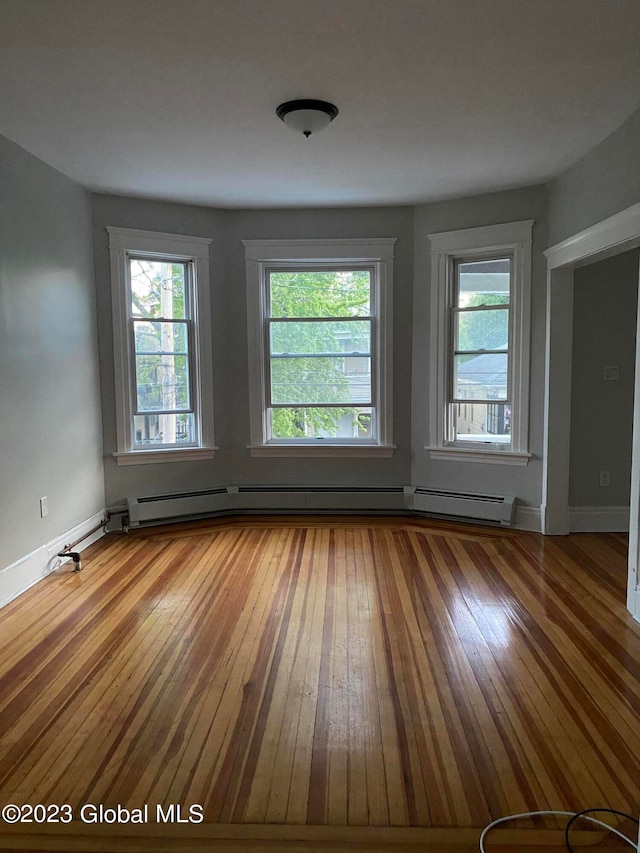 unfurnished room featuring baseboard heating and wood-type flooring