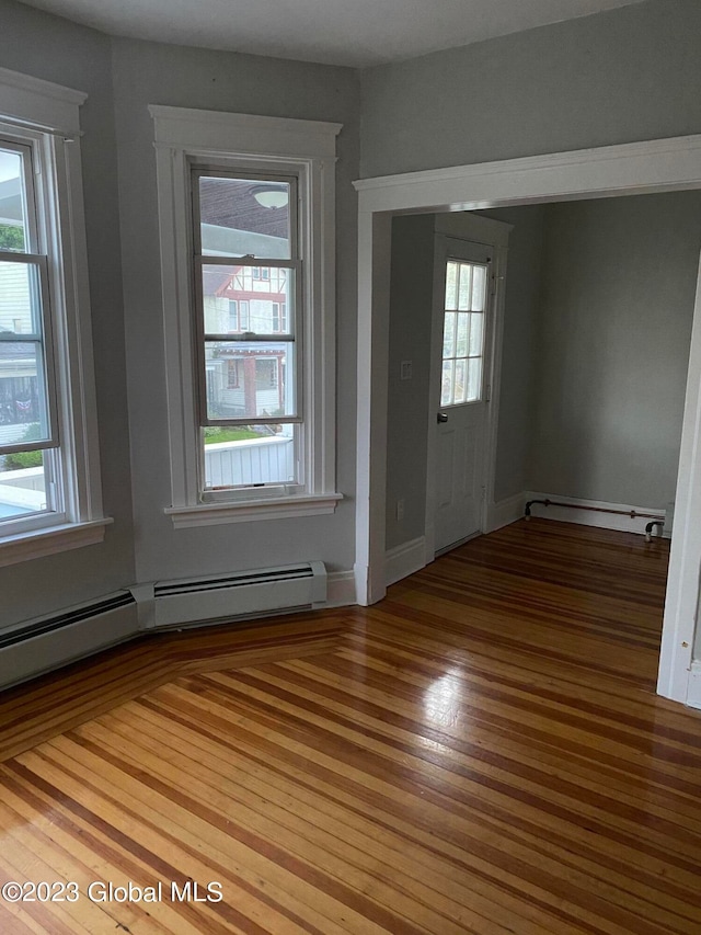 empty room with light hardwood / wood-style floors and baseboard heating