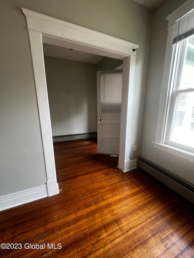 empty room with a baseboard radiator and dark wood-type flooring