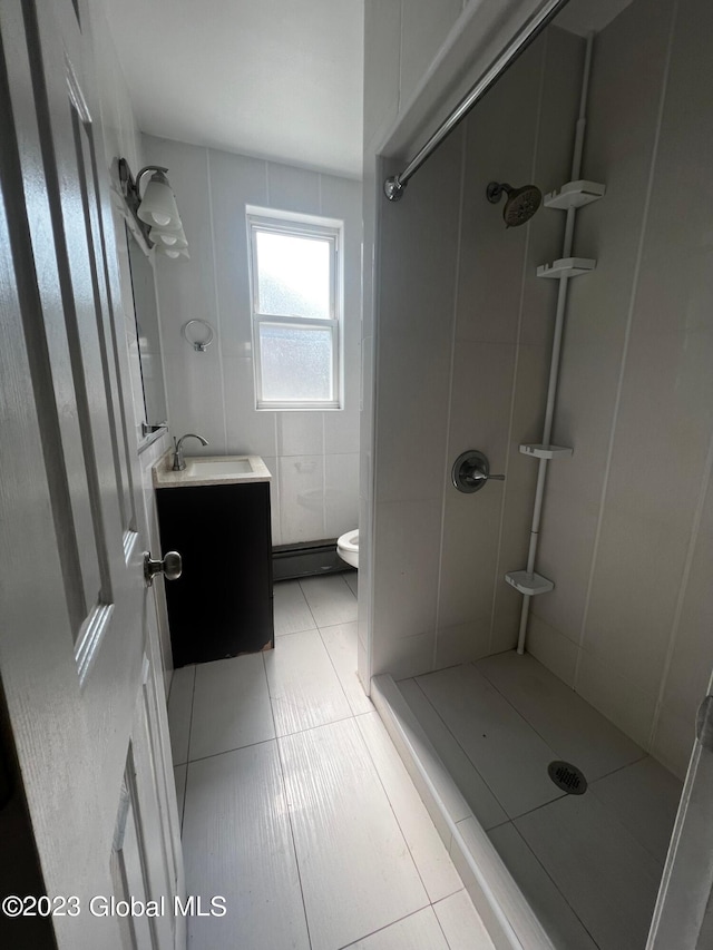 bathroom featuring tile floors, toilet, a tile shower, and vanity