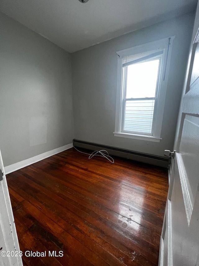 spare room with a baseboard radiator and dark hardwood / wood-style floors