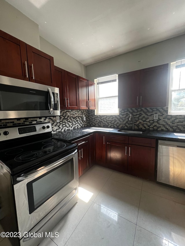 kitchen featuring backsplash, appliances with stainless steel finishes, light tile floors, and sink