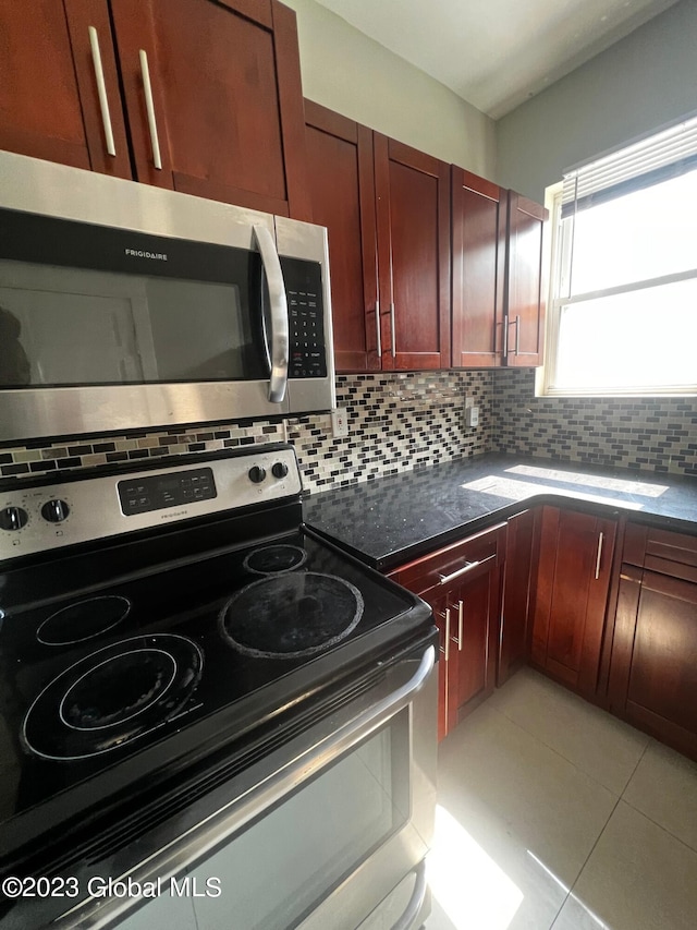 kitchen with appliances with stainless steel finishes, dark stone counters, tasteful backsplash, light tile floors, and sink