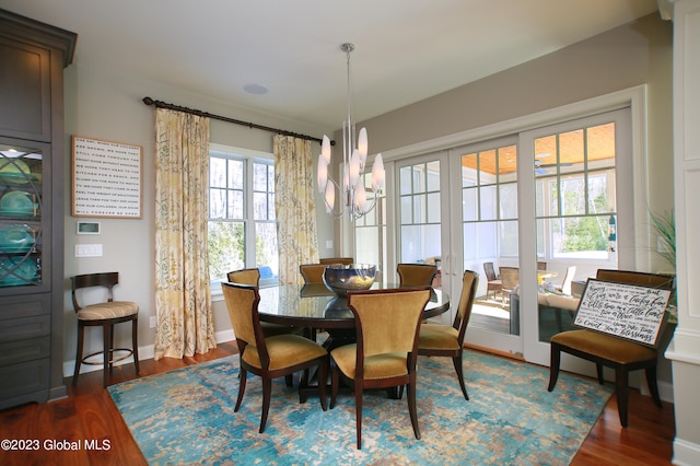 dining space with dark hardwood / wood-style floors, an inviting chandelier, and french doors