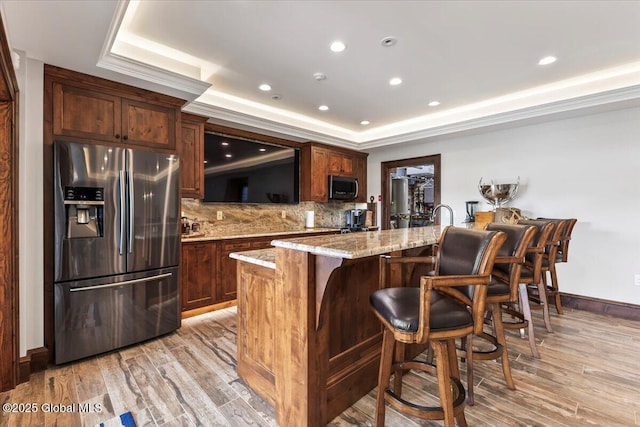 41 Trinity Rock Rd, Lake George, NY 12845 - kitchen featuring stainless steel appliances, a raised ceiling, a breakfast bar area, light stone counters, and decorative backsplash