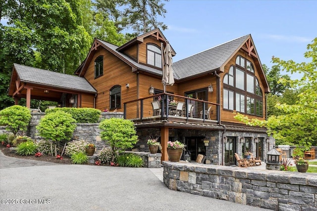 41 Trinity Rock Rd, Lake George, NY 12845 - view of front of house featuring a patio, stone siding, a balcony, and roof with shingles