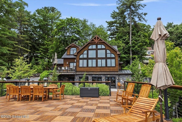 41 Trinity Rock Rd, Lake George, NY 12845 - back of house featuring outdoor dining space, stone siding, a standing seam roof, a wooden deck, and view of scattered trees