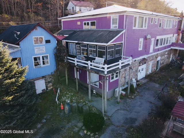 82 N Williams St, Whitehall, NY 12887 - rear view of house with a sunroom, an attached garage, a wooden deck, and metal roof