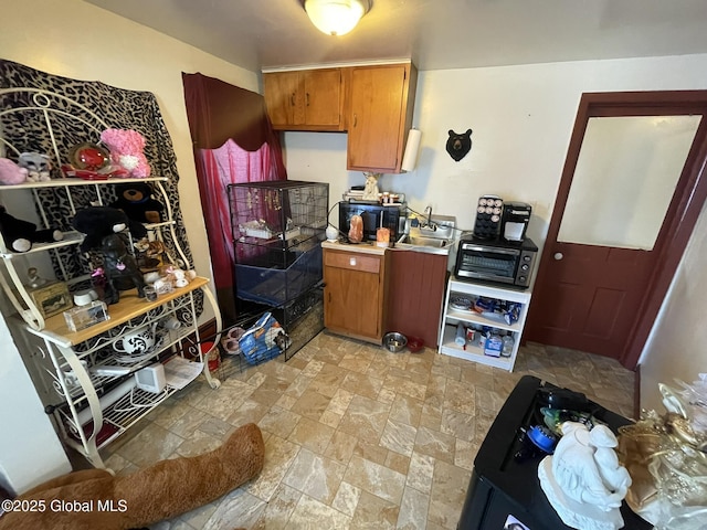 82 N Williams St, Whitehall, NY 12887 - kitchen with a toaster, light countertops, brown cabinets, a sink, and stone finish flooring