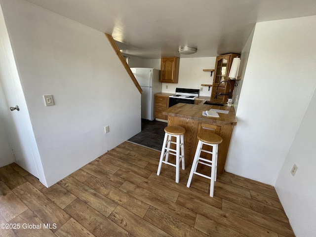 82 N Williams St, Whitehall, NY 12887 - kitchen with freestanding refrigerator, a peninsula, electric stove, a breakfast bar, and dark wood-type flooring