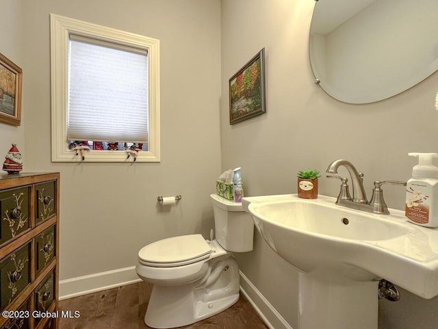 bathroom featuring toilet, baseboards, and a sink