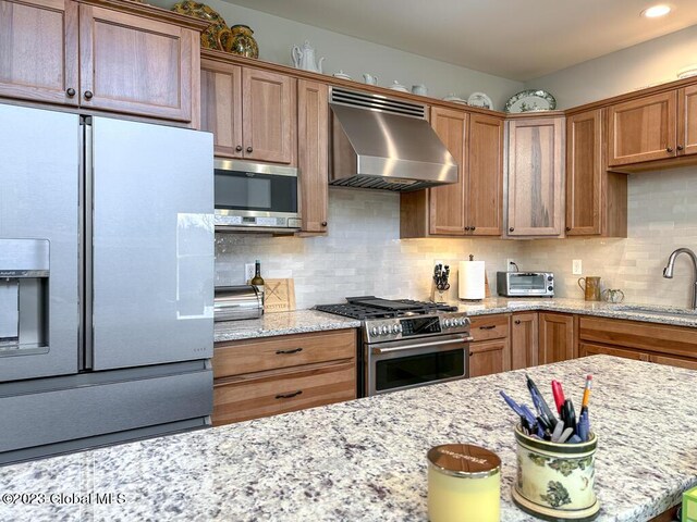 kitchen with wall chimney range hood, sink, tasteful backsplash, and stainless steel appliances