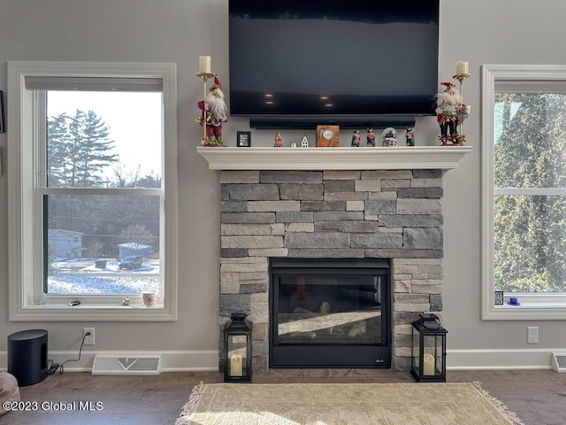 details with baseboards, a fireplace, visible vents, and wood finished floors